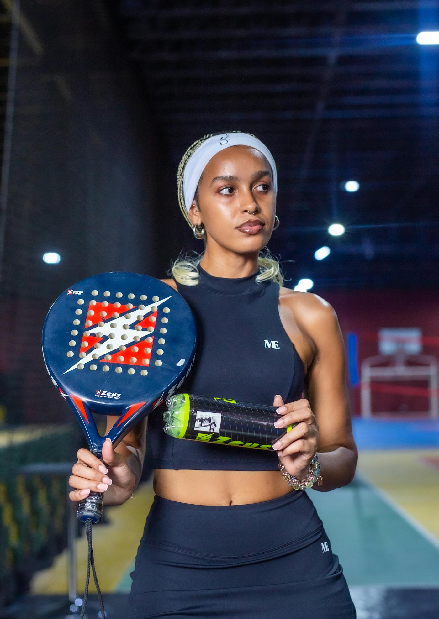 A padel player holding a racket on an indoor court